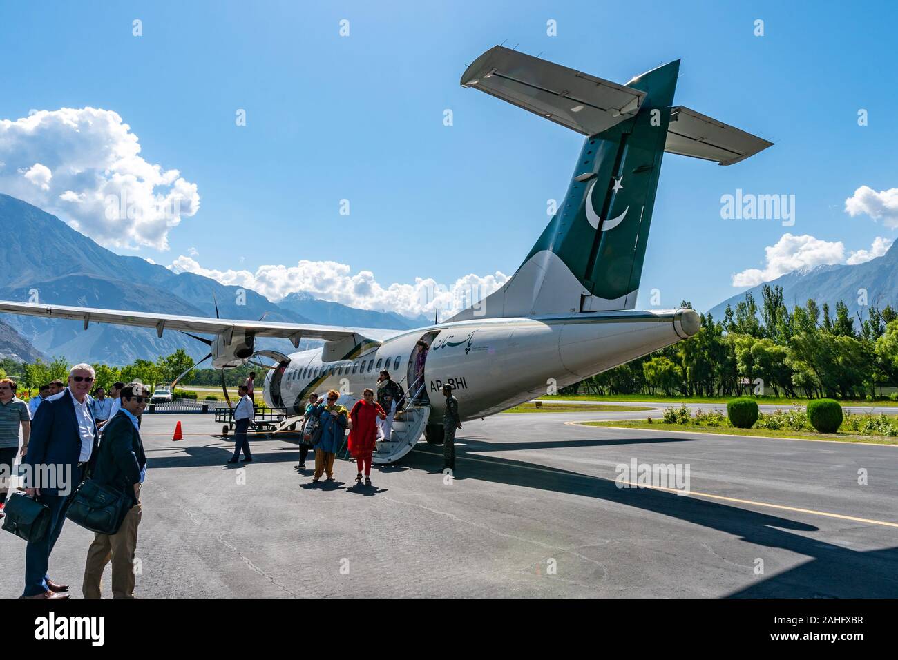Gilgit Domestic Airport Pakistan Airlines Passengers are Exiting the Plane on a Sunny Blue Sky Day Stock Photo