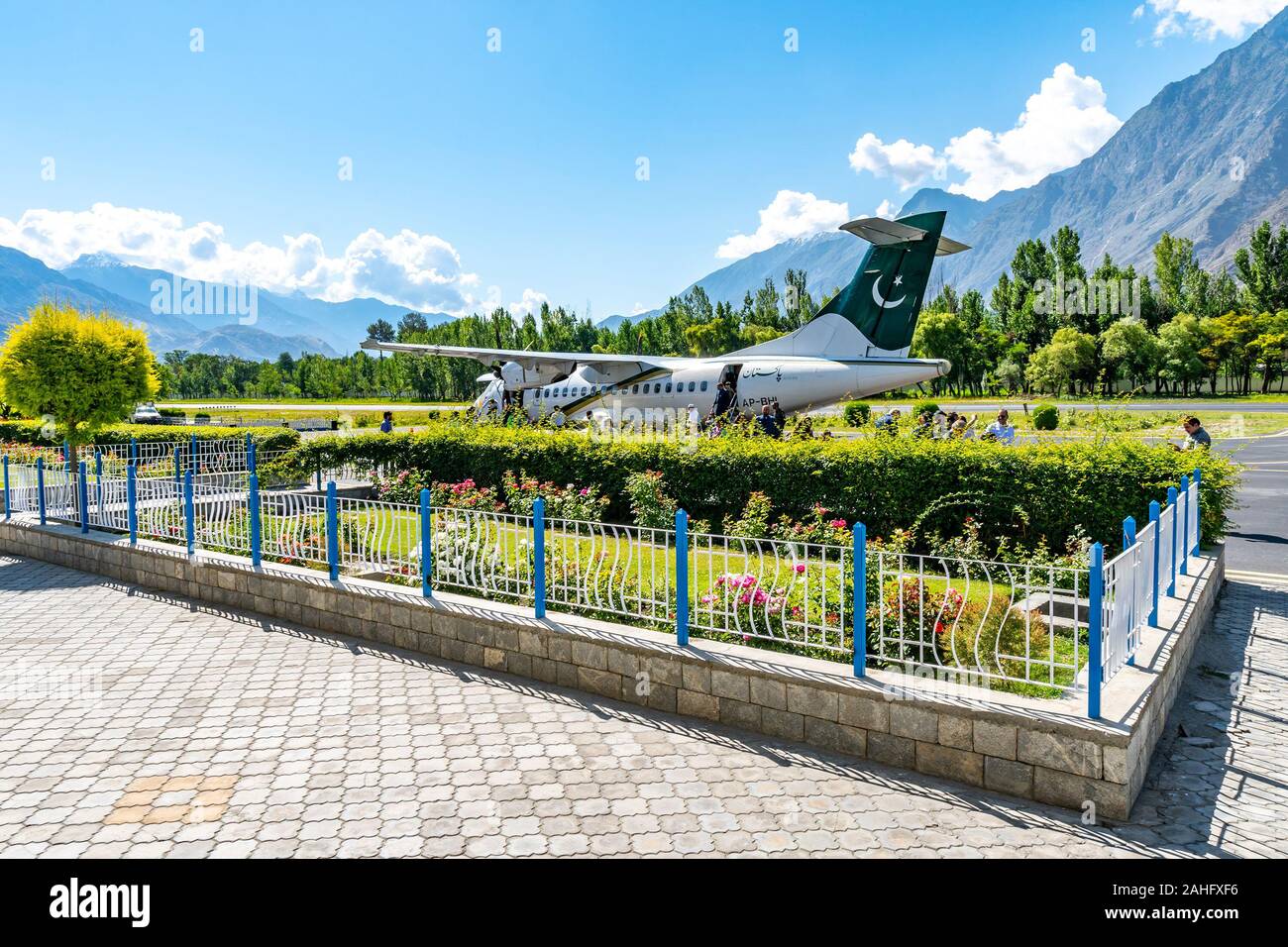 Gilgit Domestic Airport Pakistan Airlines Passengers are Exiting the Plane on a Sunny Blue Sky Day Stock Photo