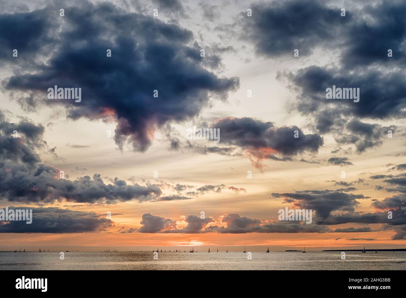 Sunset over sea. Dark dramatic clouds and distant yachts at sunset Stock Photo