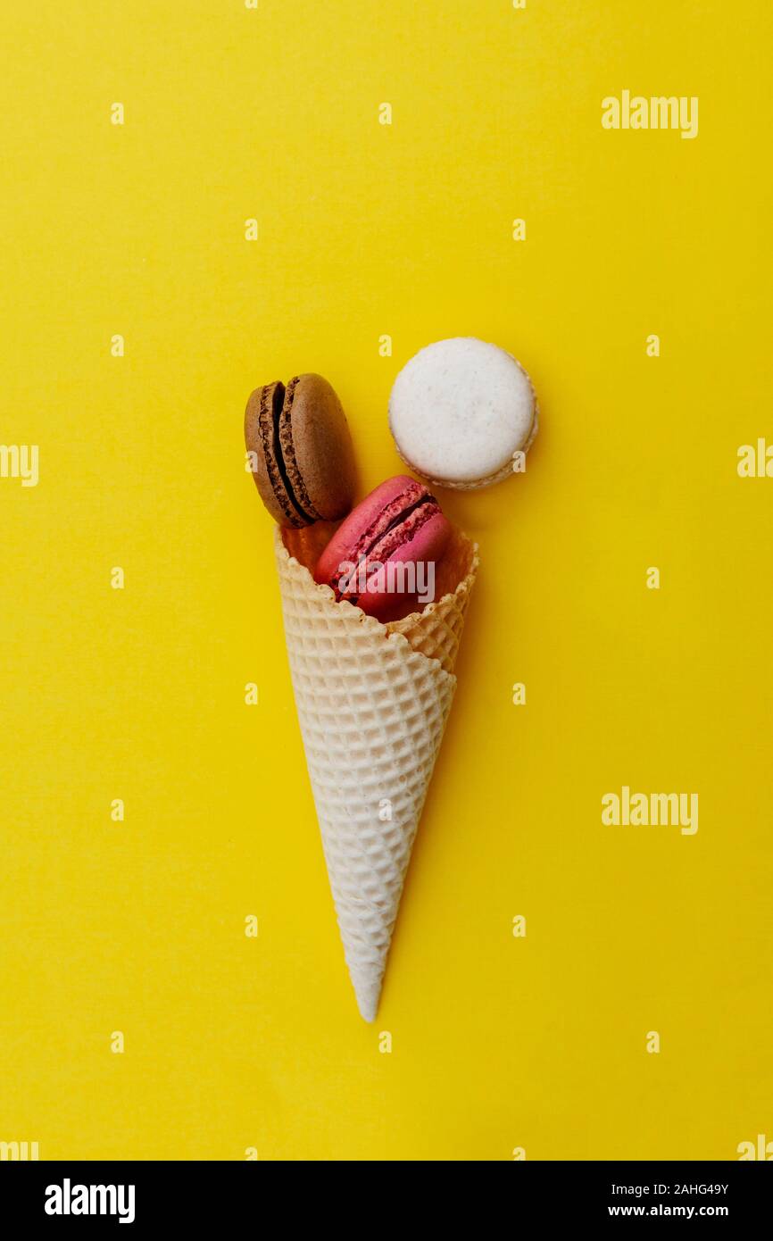 Macarons cakes. Stil life photo of waffle cone with macaroons on yellow ...