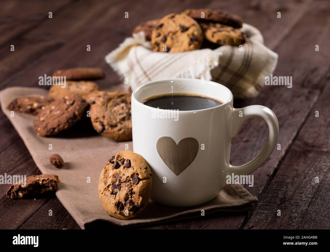 Cup of coffee with heart and chocolate chip cookies on rustic wooden