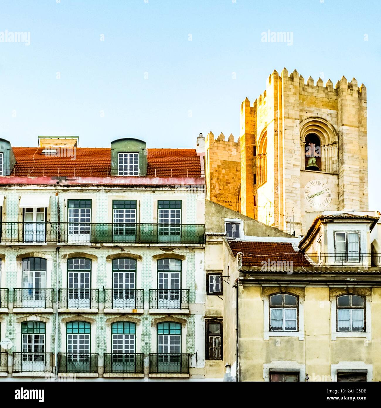 Pombaline style houses in Lisbon and bell towers of Lisbon Cathedral illuminated by sunset. Stock Photo