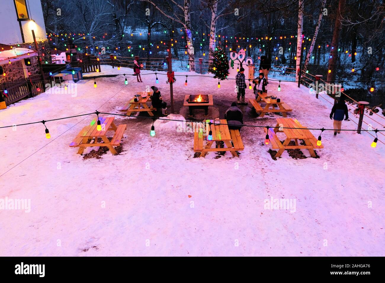 Outdoor dining in the snow with a bonfire and wooden park benches in Leavenworth, Washington, USA on a cold winter night. Stock Photo