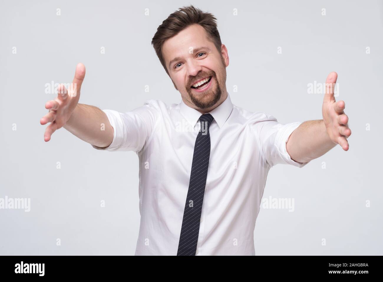 Coworker with moustache pulling hands towards camera and smiling friendly at camera wanting hug Stock Photo