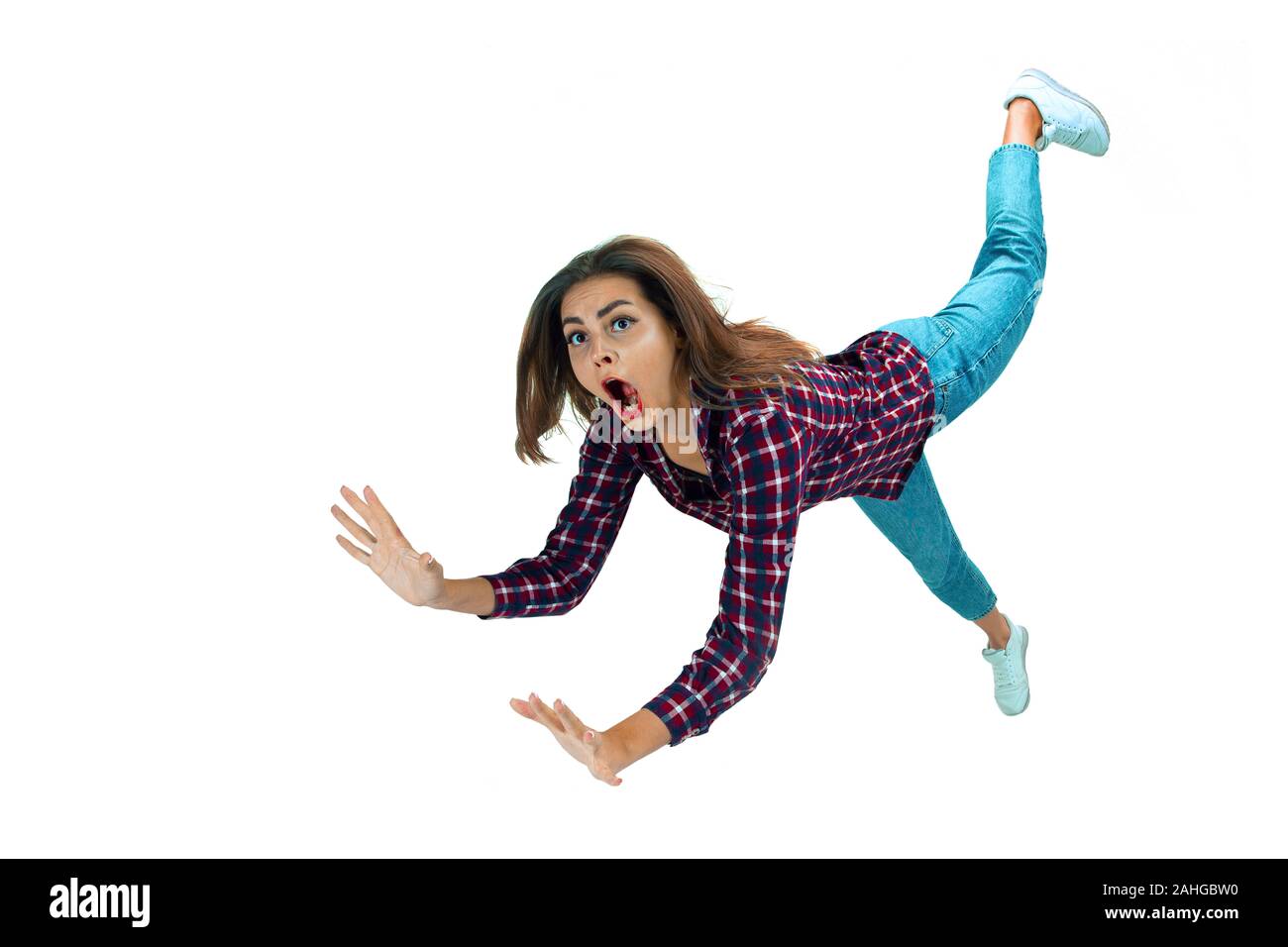A second before falling. Caucasian young girl falling down in moment with bright emotions and facial expression. Female model in casual clothes. Shocked, scared, screaming. Copyspace for ad. Stock Photo