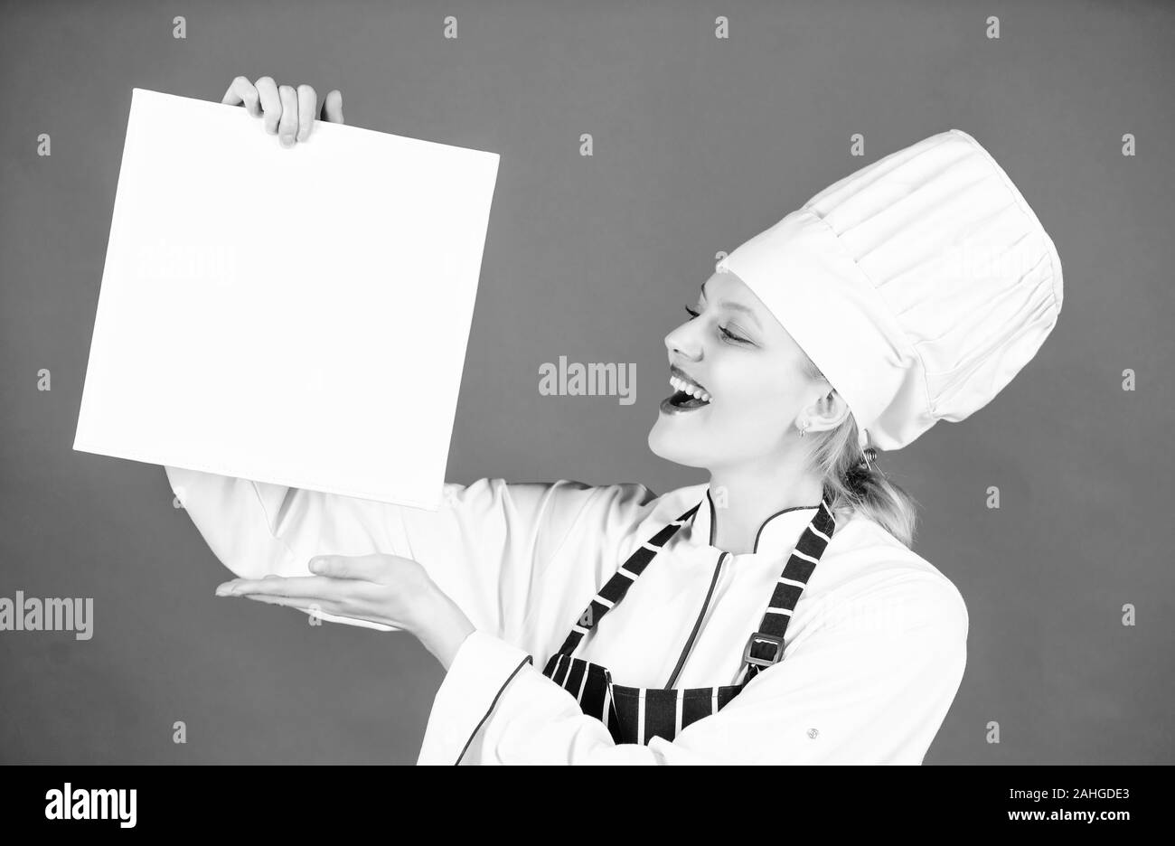 woman in cook hat and apron. restaurant menu. Culinary dieting. happy woman cooking healthy food by recipe. professional chef in kitchen. Cuisine. Housewife with cookery book. feels hunger. Stock Photo