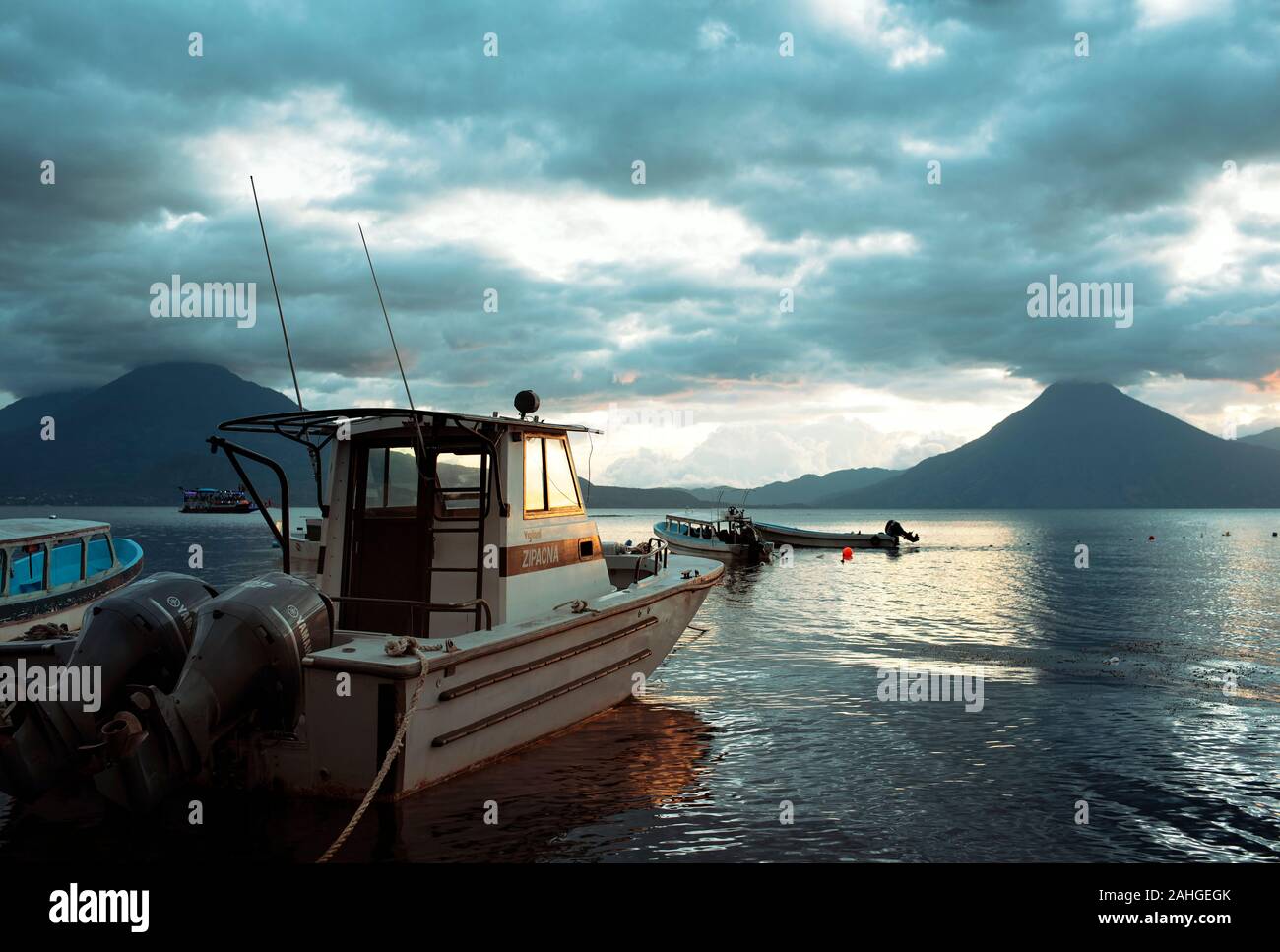 Fishing boat with dramatic, cloudy sunset and volcanoes. Lake Atitlán, Guatemala. Dec 2018 Stock Photo