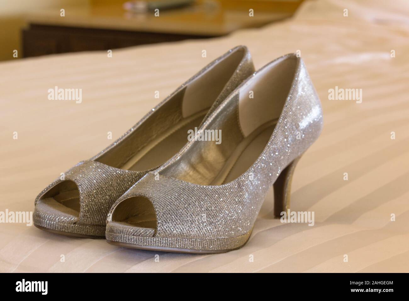Bride's silver shoes on white cover sheet bed. Wedding ceremony preparation concept Stock Photo