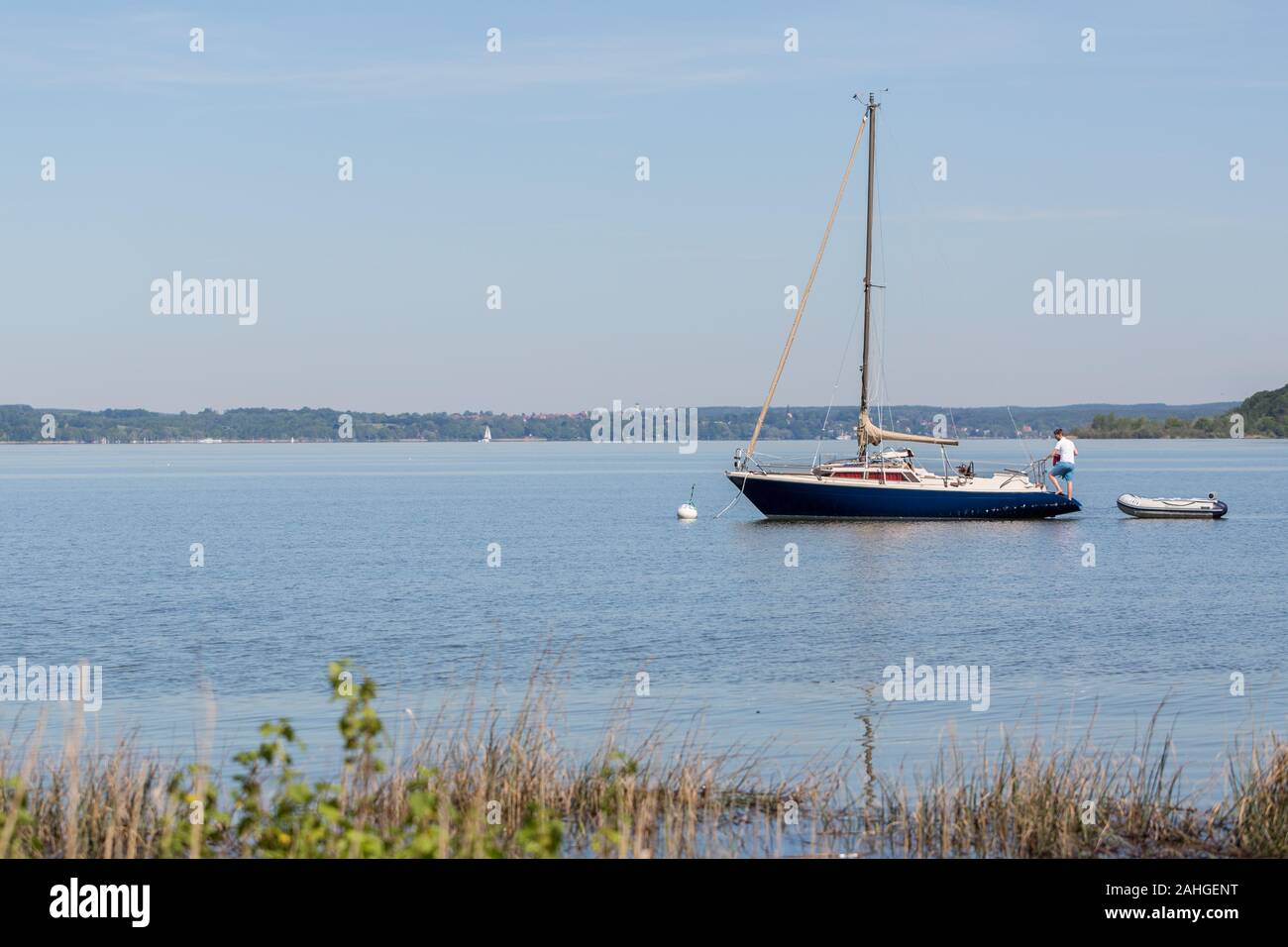 View on blue and white colored sailboat at Lake Ammersee. Sailing is a common activity in the upper bavarian five-lakes-region. Stock Photo