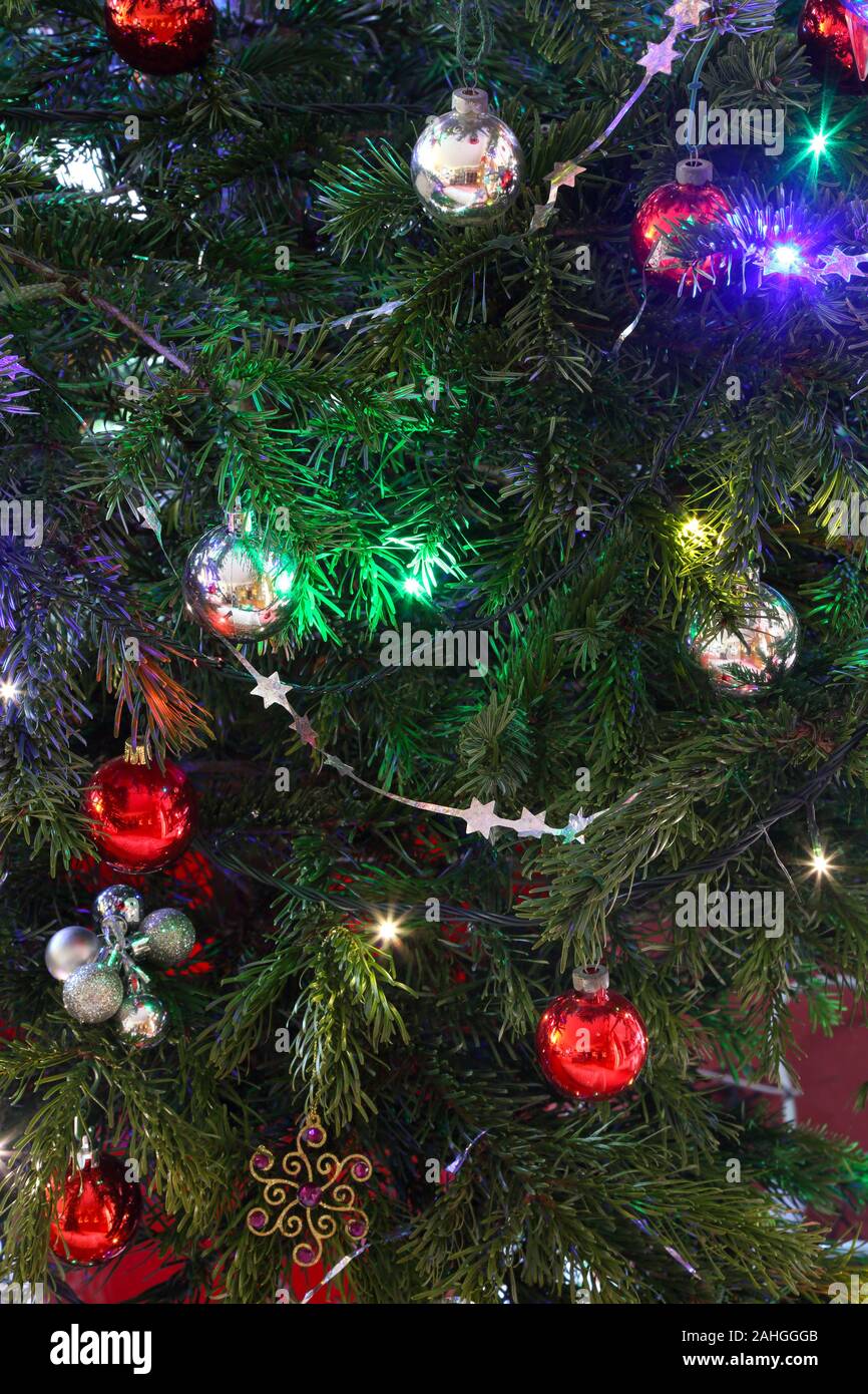 Decorations on Christmas tree, baubles, tinsel and lights in close-up. Stock Photo