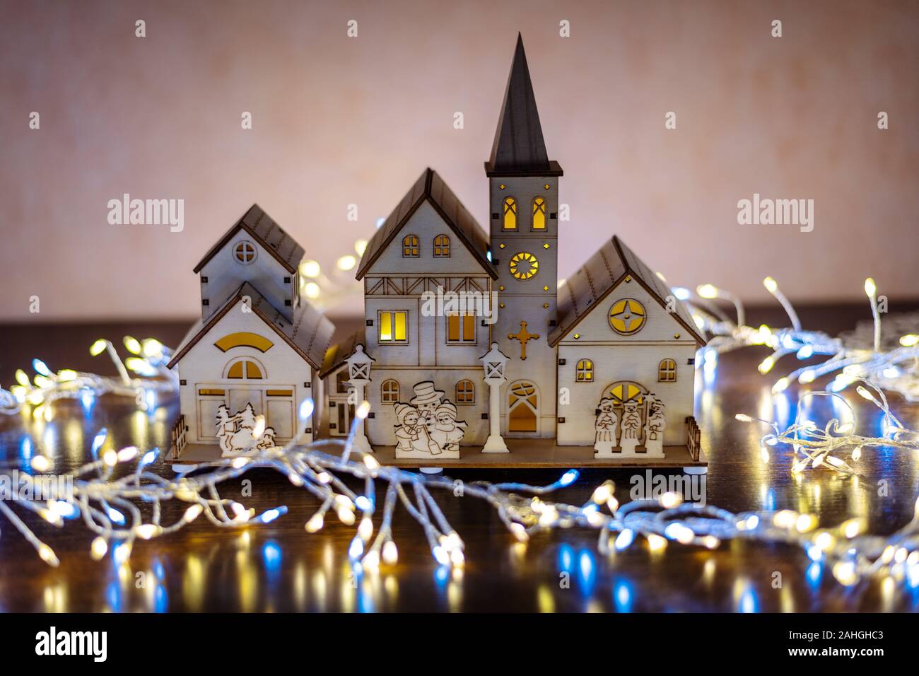 Christmas background with a wooden village illuminated, surrounded by led light tinsel. Stock Photo