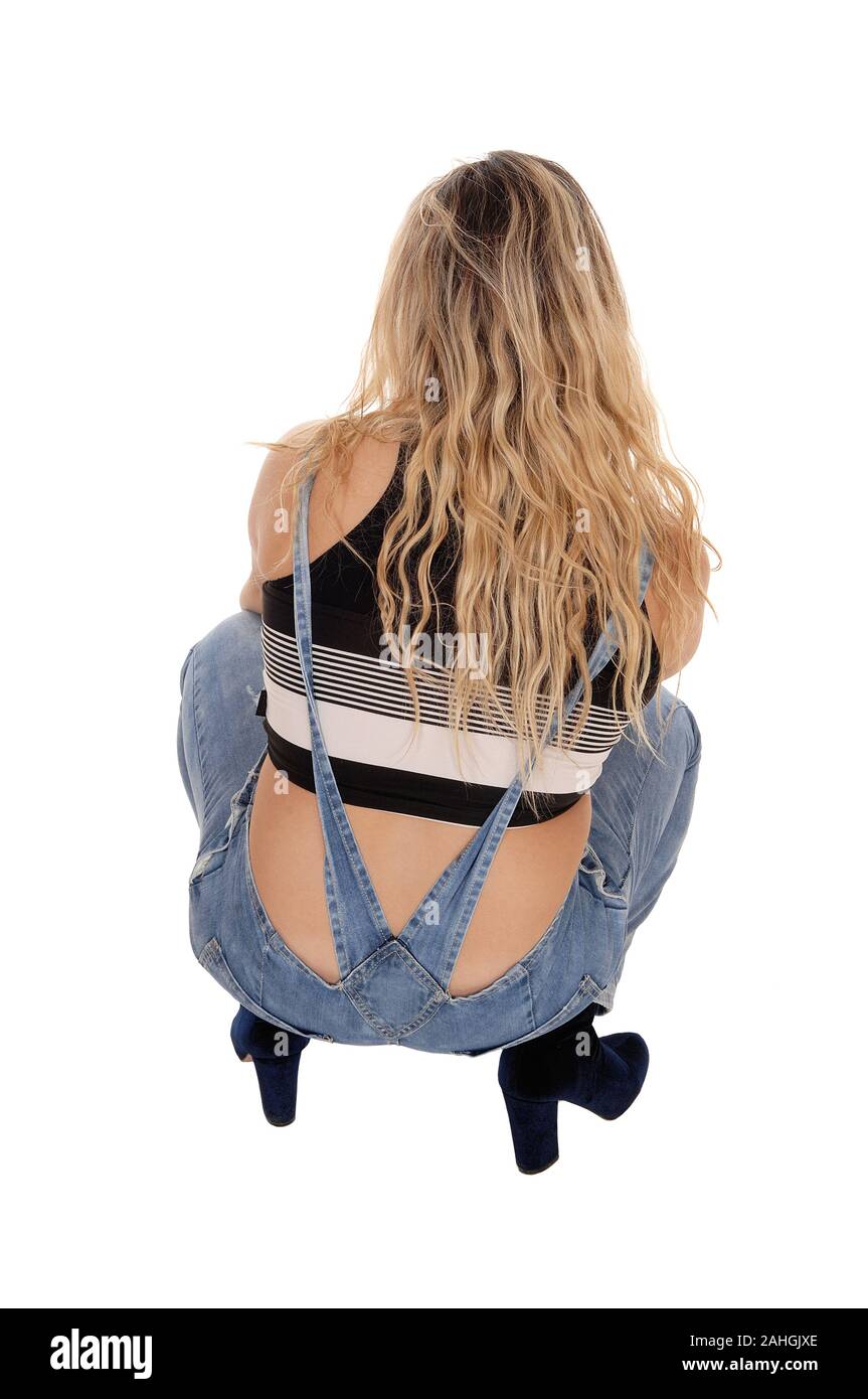 A lovely young blond woman in working jeans crouching on the floor in the  studio from the back, isolated for white background Stock Photo - Alamy