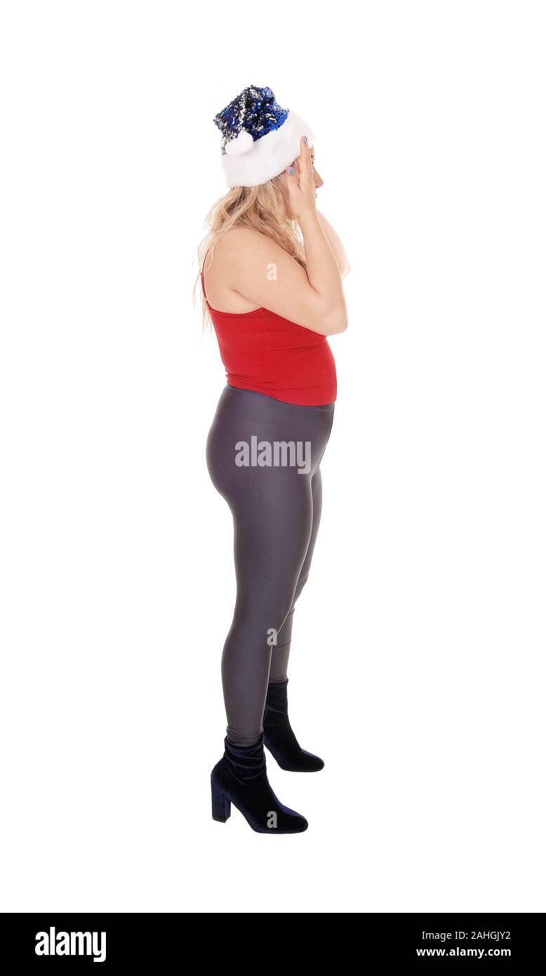 A beautiful young woman standing in profile in black tights and red top with a Santa hat, isolated for white background Stock Photo