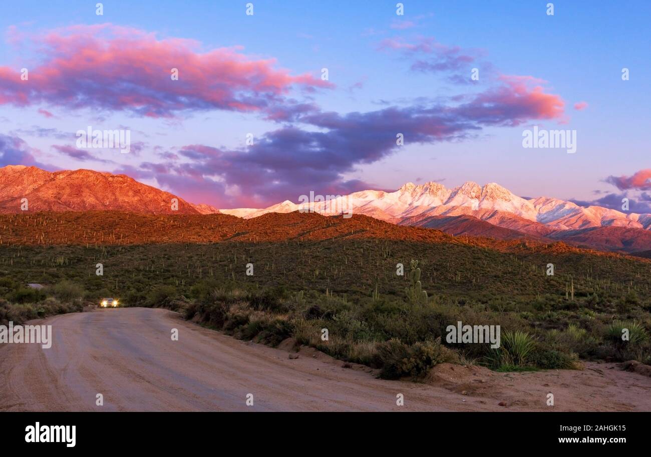 Sunset Image of the Snow covred Four Peaks Mountain Range with SUV on rough road  Outside Phoenix AZ after storm Stock Photo