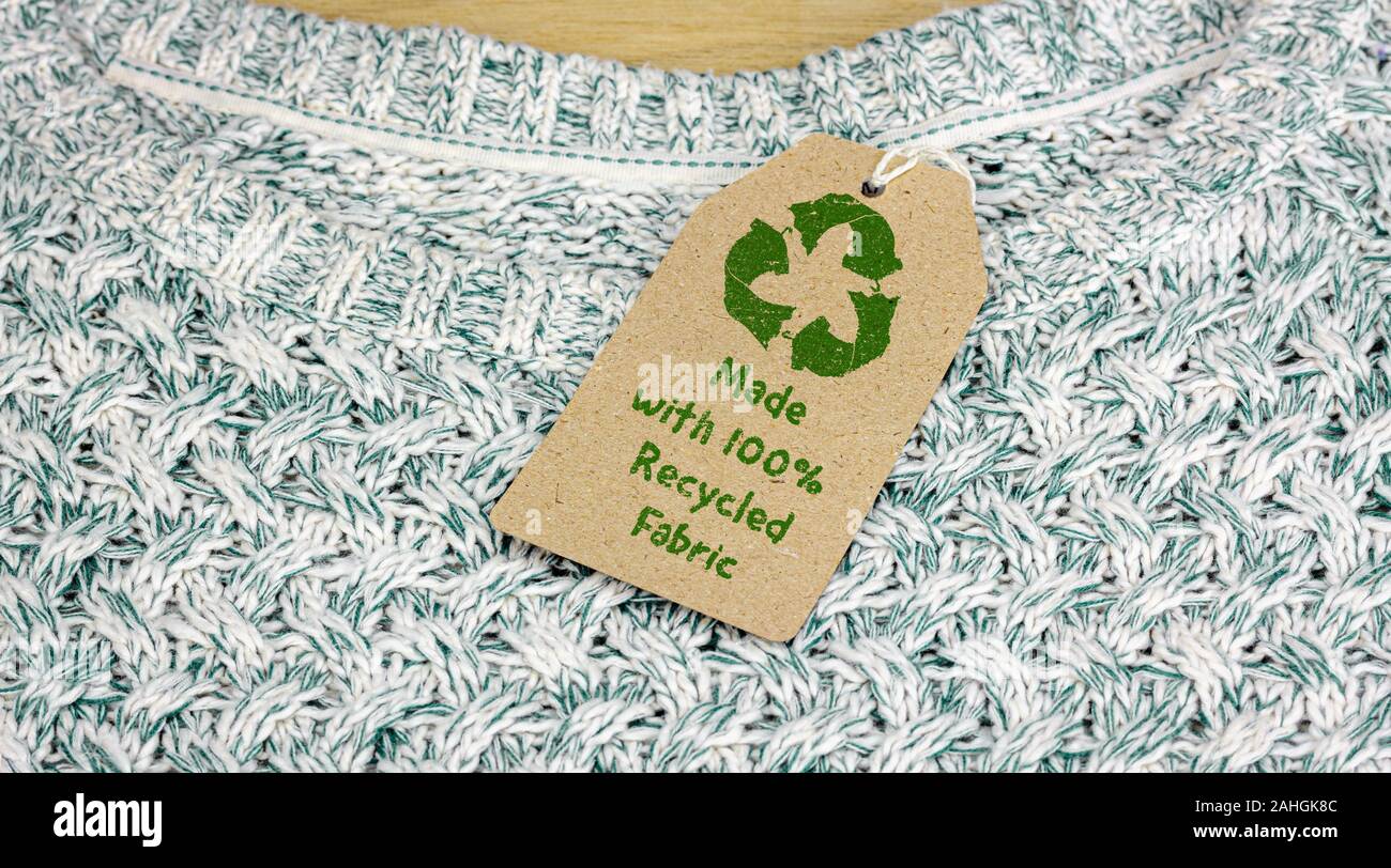 Recycle clothes icon on recycled card label, made with 100