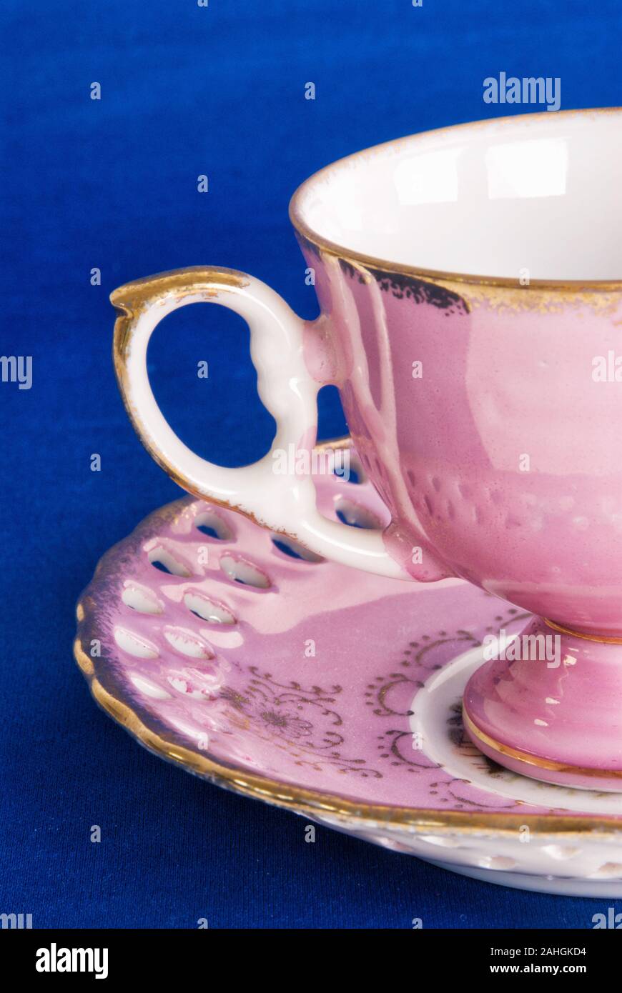 https://c8.alamy.com/comp/2AHGKD4/antique-pink-colored-cup-with-matching-saucer-on-a-blue-textured-background-2AHGKD4.jpg