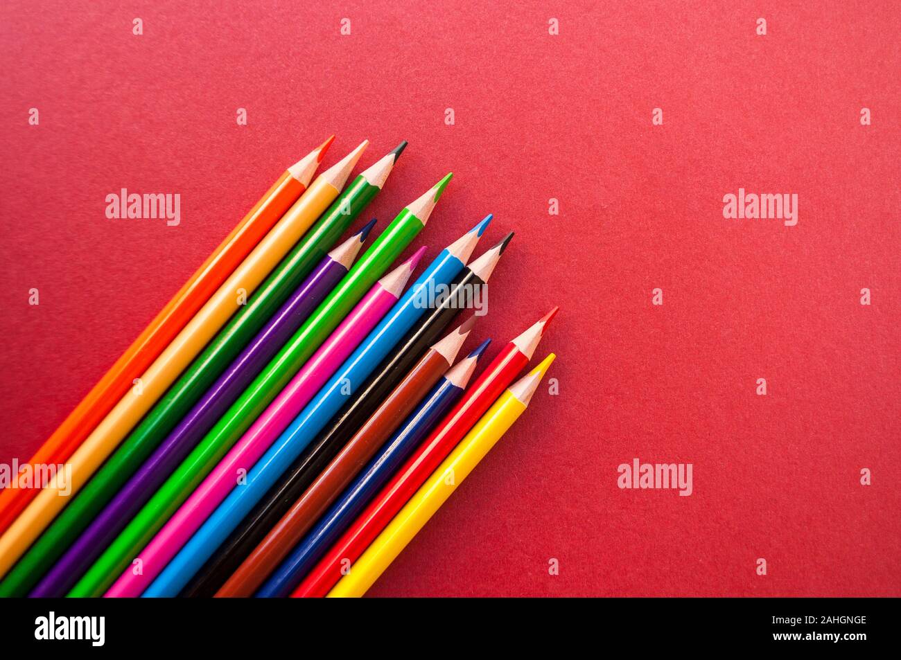 Colorful pencils on red background with copyspace. Stock Photo