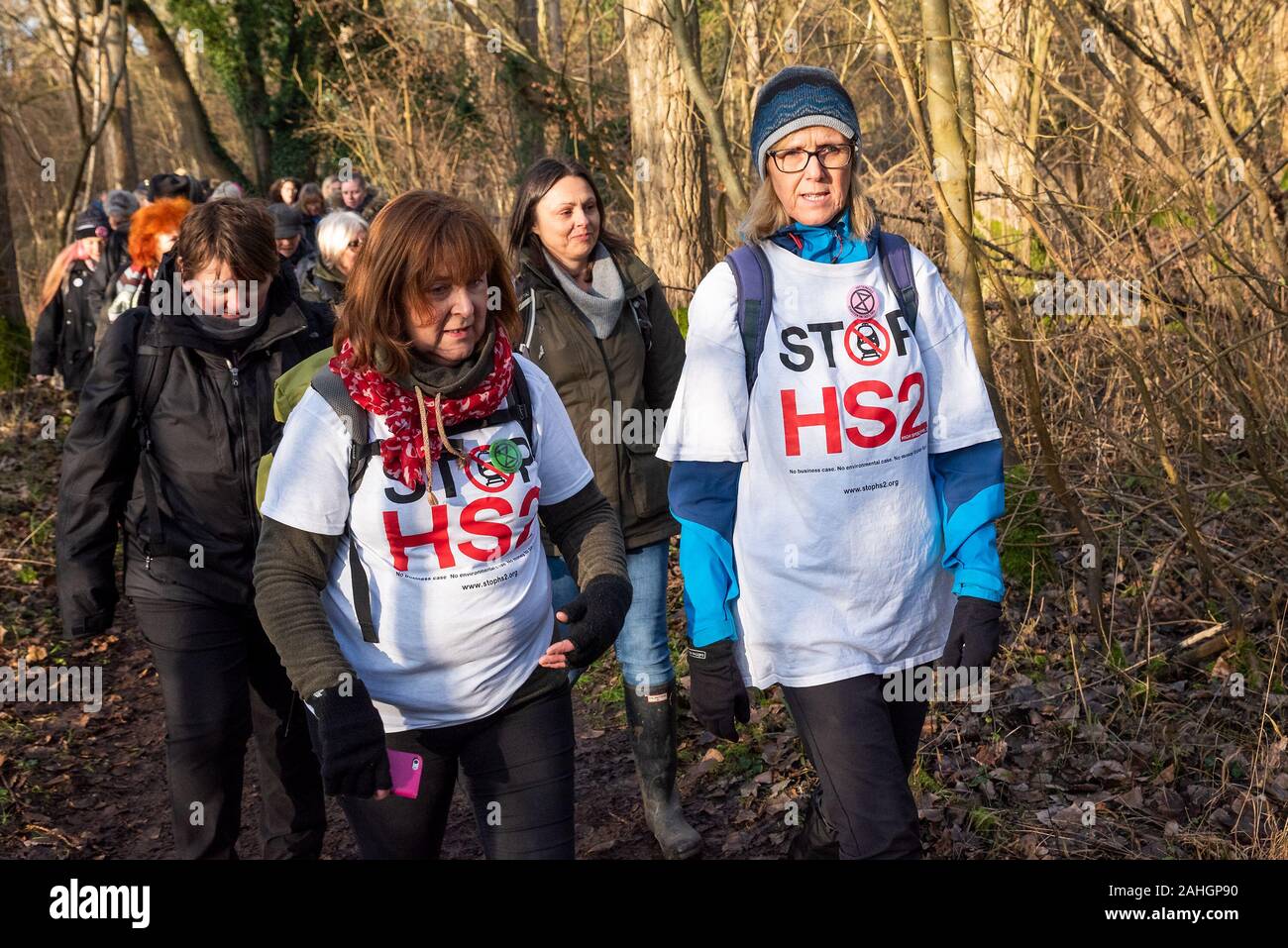 Denham, UK. 29th December 2019. Stand for the Trees, a Walk for Wildlife and Water, organised by Chris Packham and supported by Extinction Rebellion, #ReThinkHS2, Save the Colne Valley, STOP HS2 and Hillingdon Green Party. Speakers described the threats to the habitats that are the homes of endangered eels, bats, otters, water voles, the loss of 28,000 trees to HS2 and the chalk aquifer that contributes to much of London’s water. Pictured, 2 women campaigners wearing Stop HS2 tee shirts walking through woodland. Credit: Stephen Bell/Alamy Stock Photo