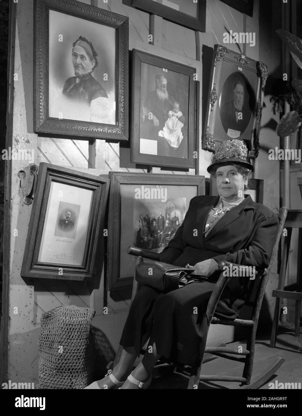 Woman seated in front of portraits of family members, 1946. This was part of the Minnesota State Fair in 1946, where people stood in front of portraits of their grandparents to illustrate genealogical traits. One of the portraits bears the name Louis E. Torinus Stock Photo