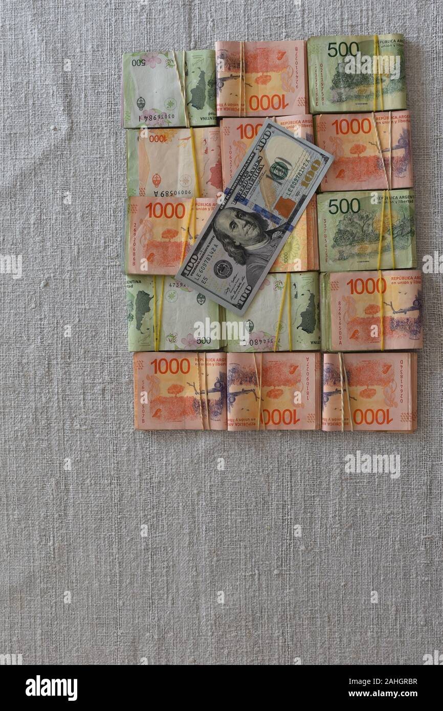 100 dollar bill with Argentine peso bills symbolic for money