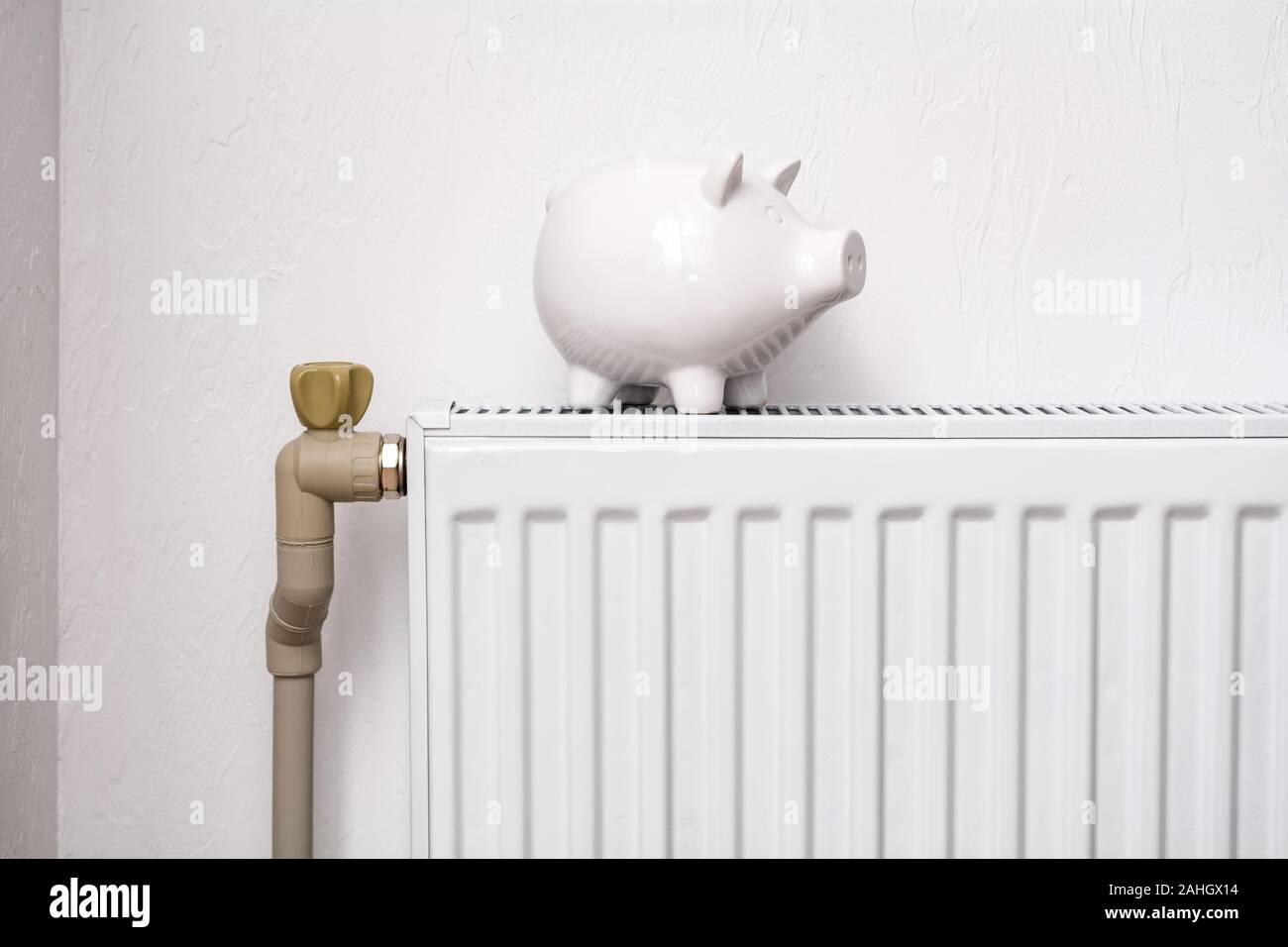 White pig piggy bank on radiator. Expensive heating costs concept Stock Photo