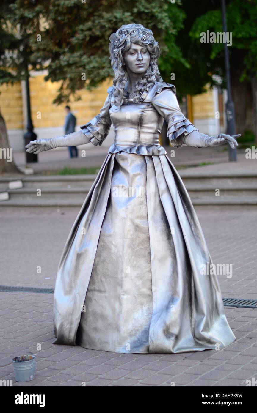 Living sculptures. Painted in silver color on the street posing a man and a woman in beautiful, vintage outfits .Russia. Stock Photo