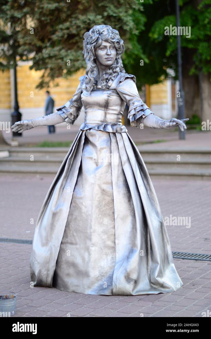 Living sculptures. Painted in silver color on the street posing a man and a woman in beautiful, vintage outfits .Russia. Stock Photo