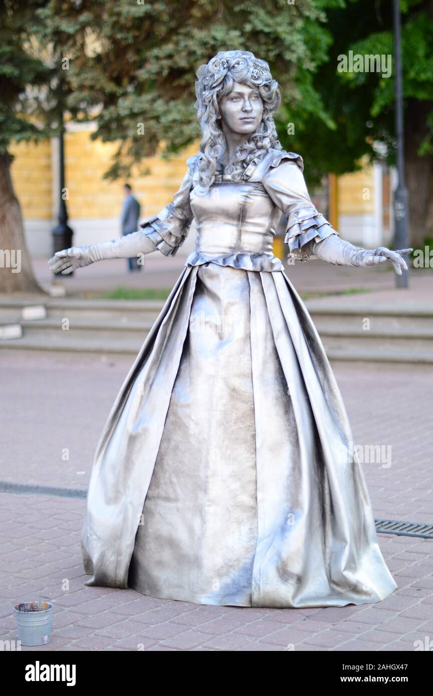 Living sculptures. Painted in silver color on the street posing a man and a woman in beautiful, vintage outfits .Russia. Stock Photo