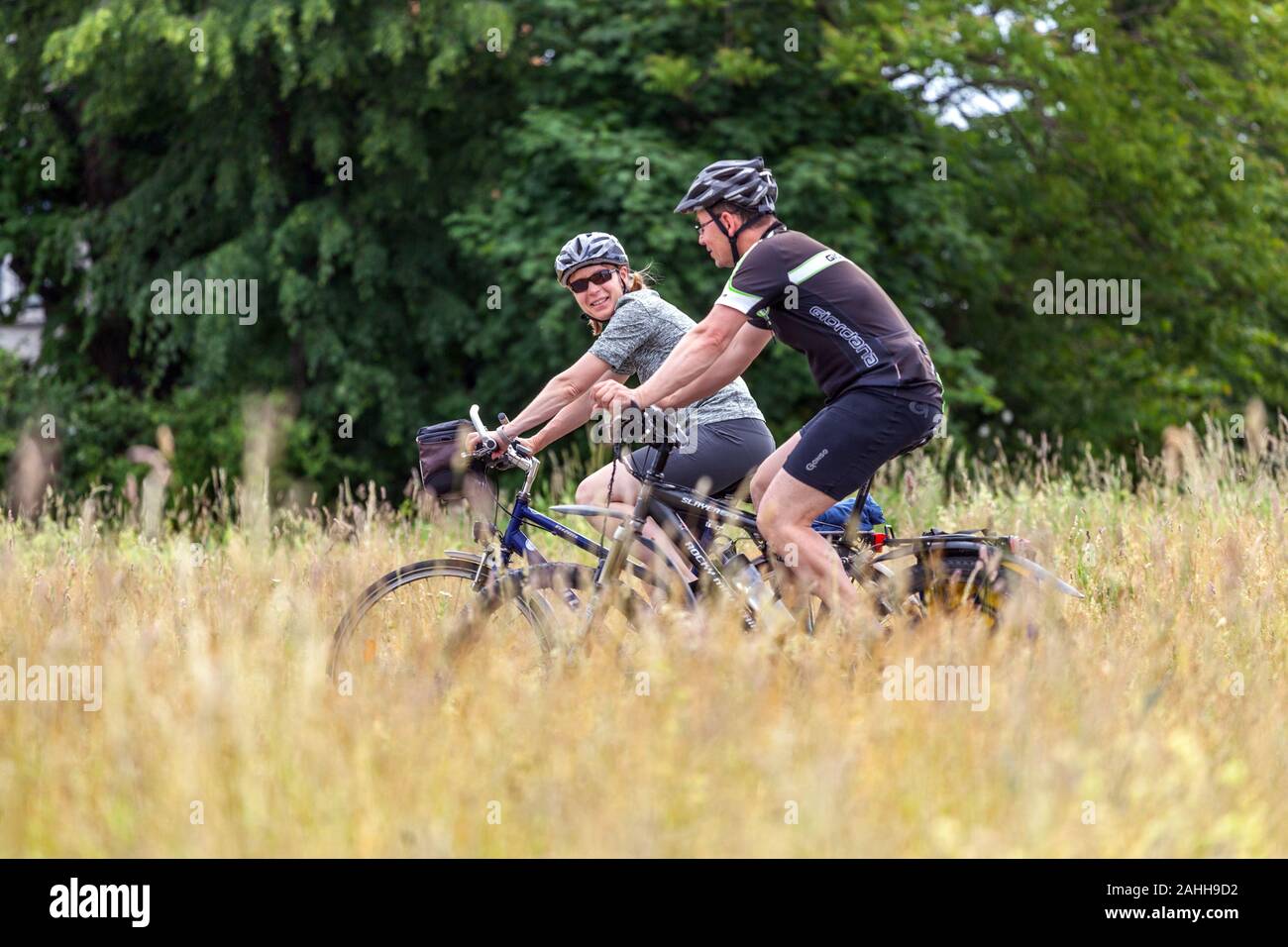 Couple riding on a bicycle on Germany cycle path and enjoying an active lifestyle Germany cycling Dresden Elbe river meadow Saxony vacation Stock Photo