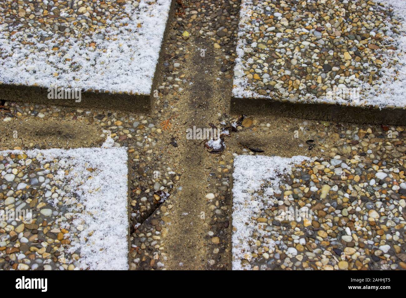 Cross made of paving tiles. In the middle of the sand, the pavement is snowy. Stock Photo