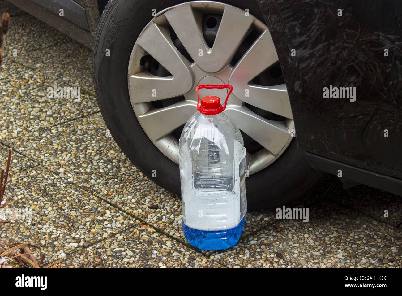 Windscreen washer antifreeze stands in front of the wheel of a black car Stock Photo