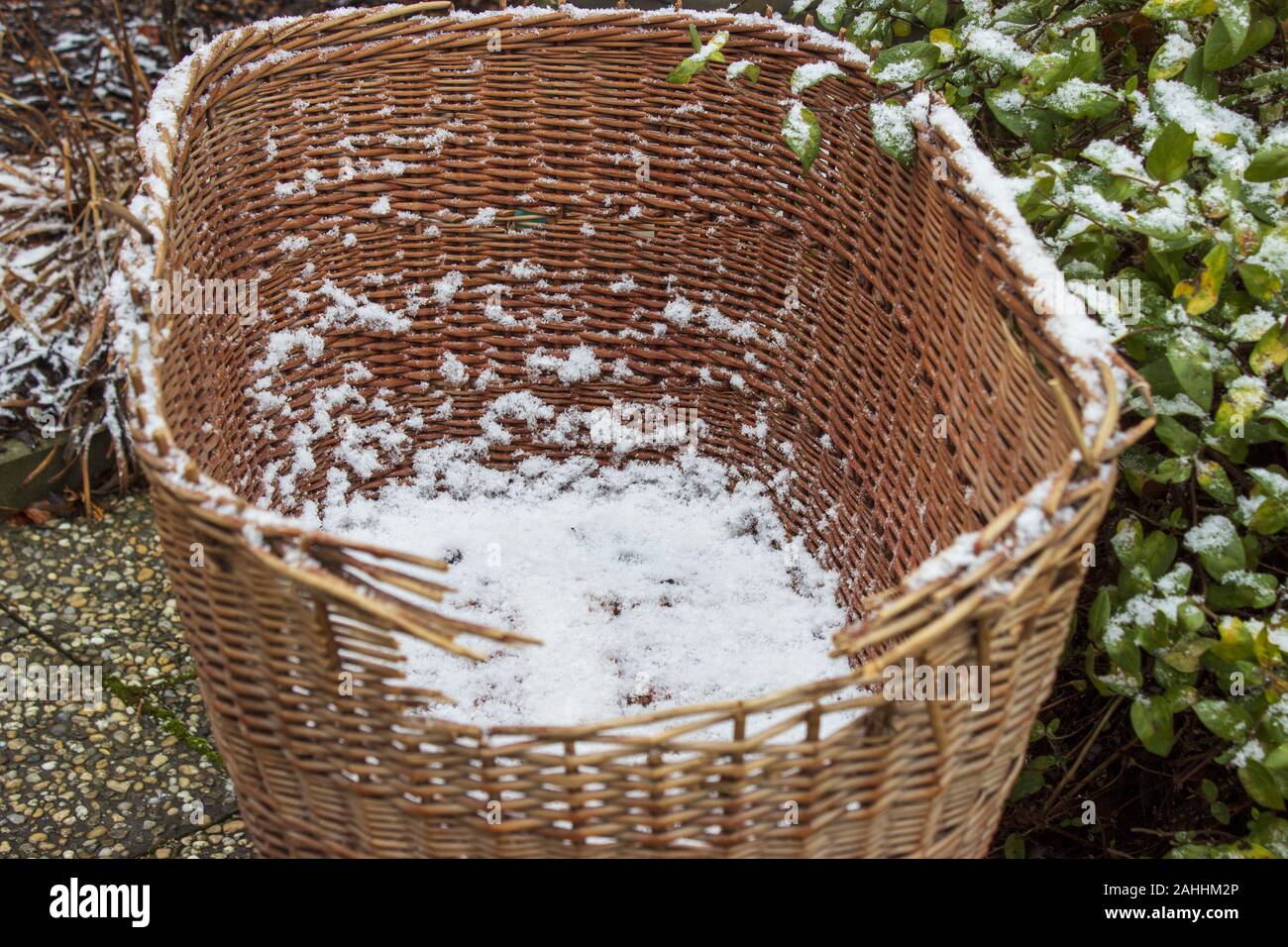 Snowy old damaged wicker basket for baby on wheels on the garden in