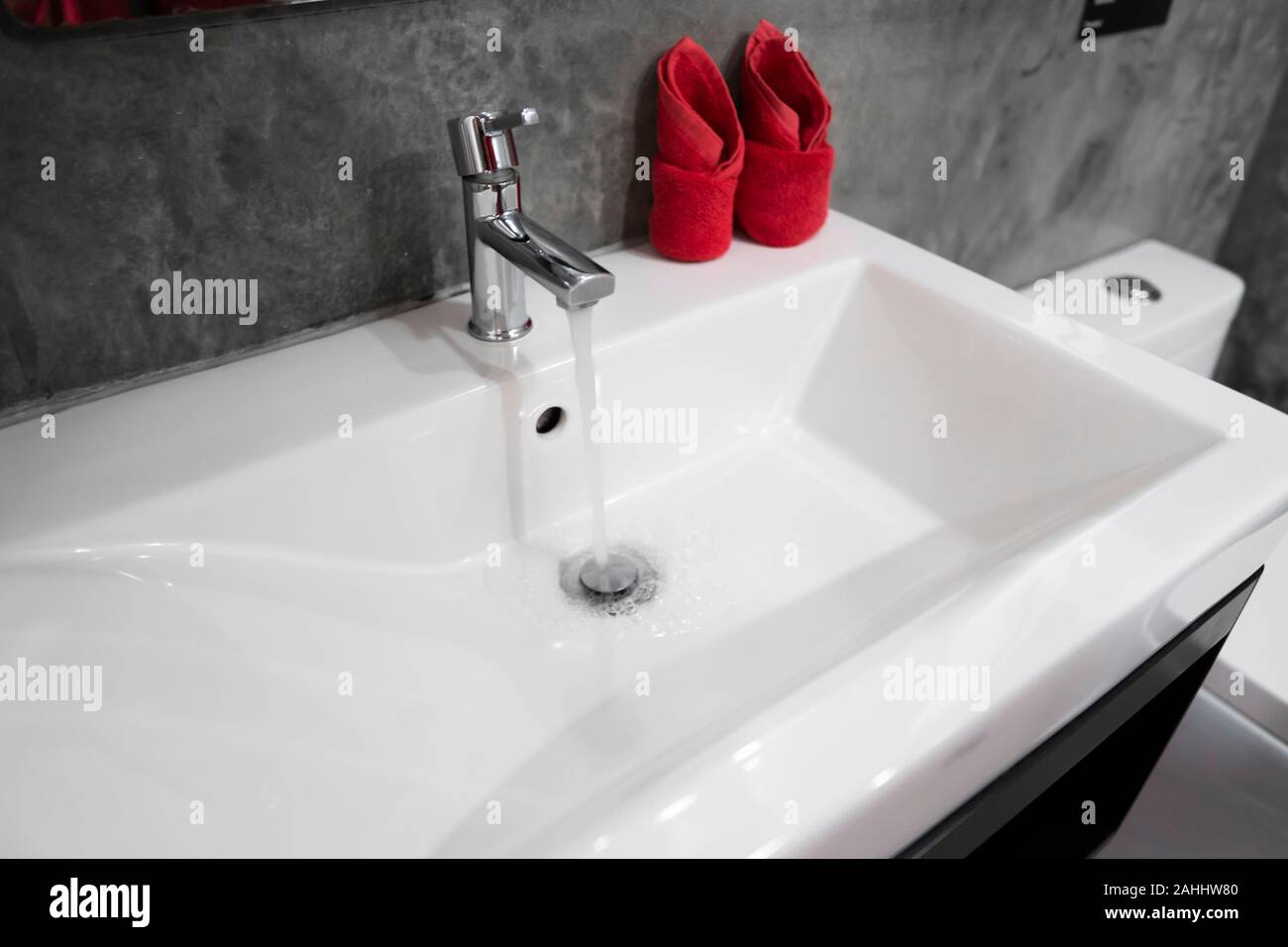 Running Water From Modern Stainless Steel Faucet In White Sink