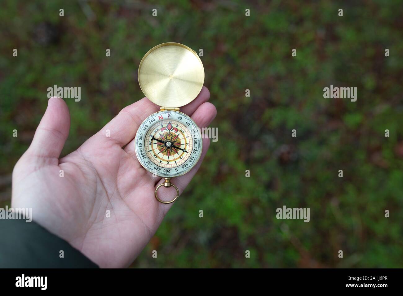 A person disoriented by the fog tries to find the right path with a compass Stock Photo