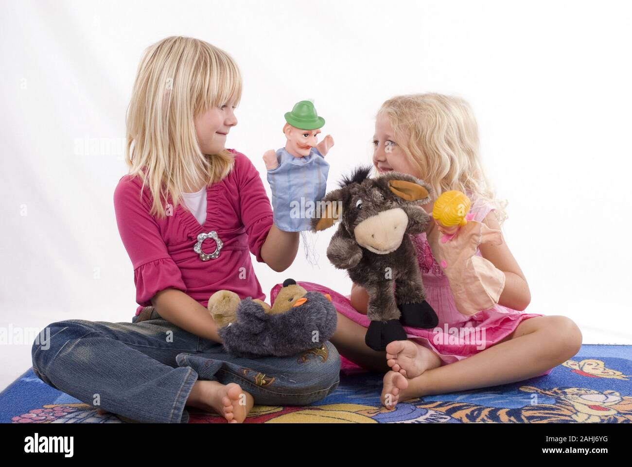 Zwei blonde Mädchen, 6 und 7 Jahre alt,  spielen mit Handpuppen, Kasperle, Figuren, Theater, Freunde, Geschwister, Kasperletheater, MR:Yes Stock Photo