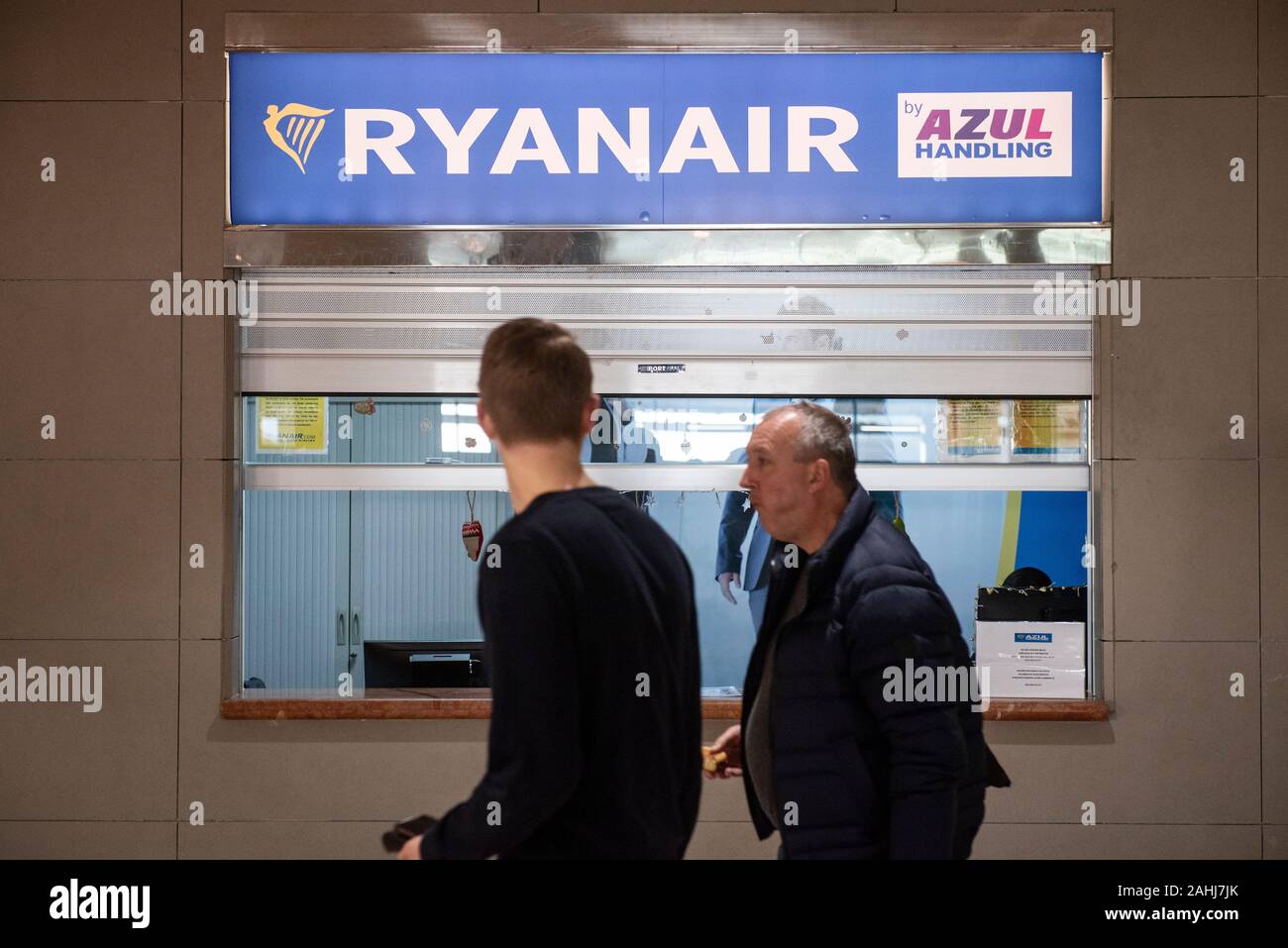Passengers walk past the Irish low-cost airline Ryanair luggage enquiry desk in Alicante airport. Stock Photo