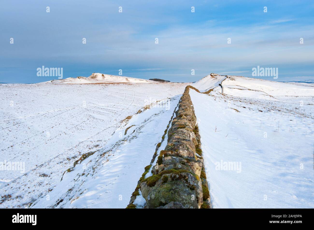 Winter in remote empty Northumberland countryside. Hadrian's Wall receding into the distance over snow covered hills on a cold frosty winters day. Stock Photo