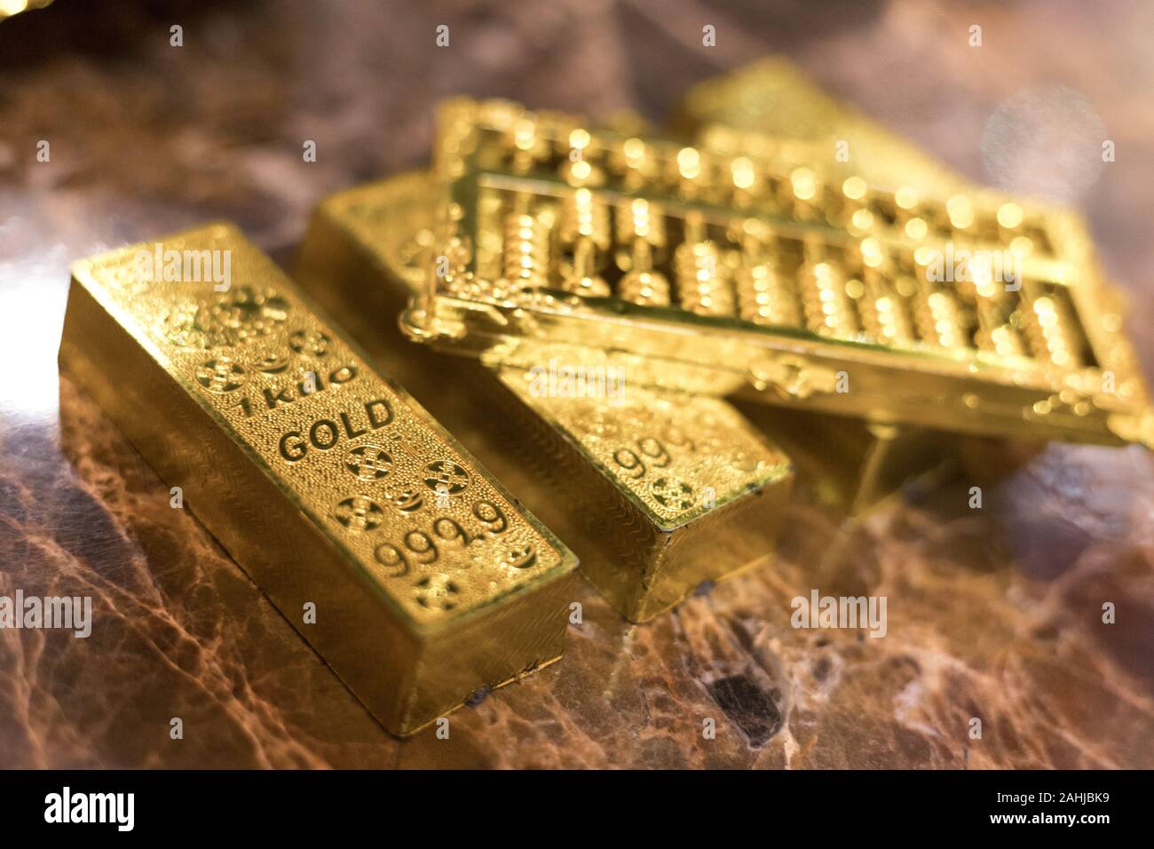 one kilo gold put on luxury marble table together in a row with golden abacus on top. closeup Stock Photo