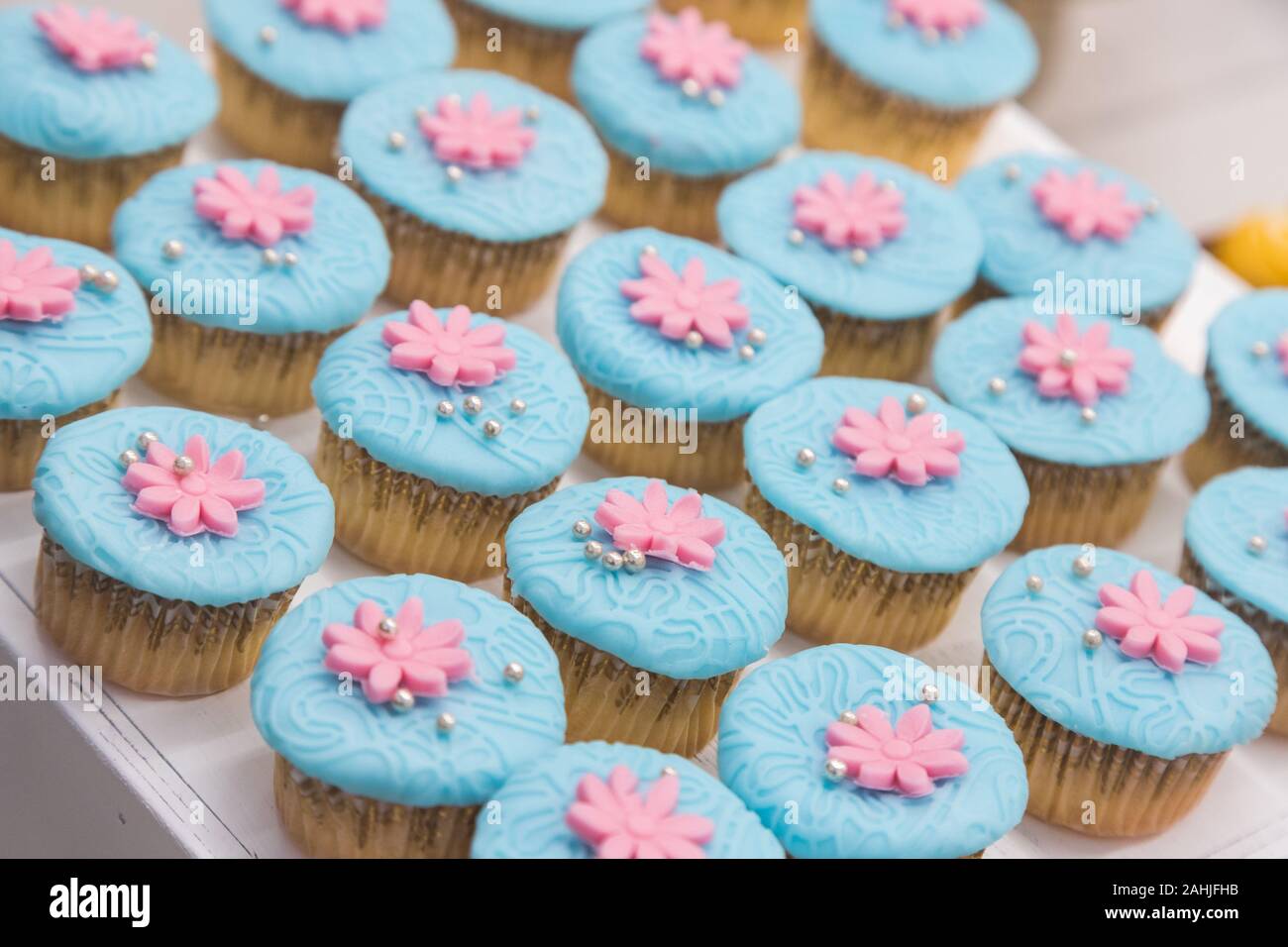 cupcakes with different topping, it have sofe blue cream flat on top and some snack like flower with mini ball. they're all put together in pattern Stock Photo