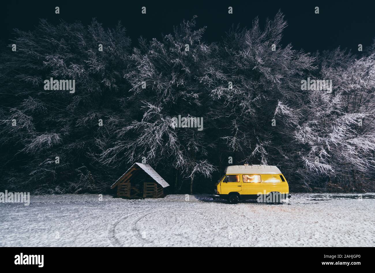 Carpathians, Ukraine - December 2019: yellow camper van with winter snowy forest on background Stock Photo