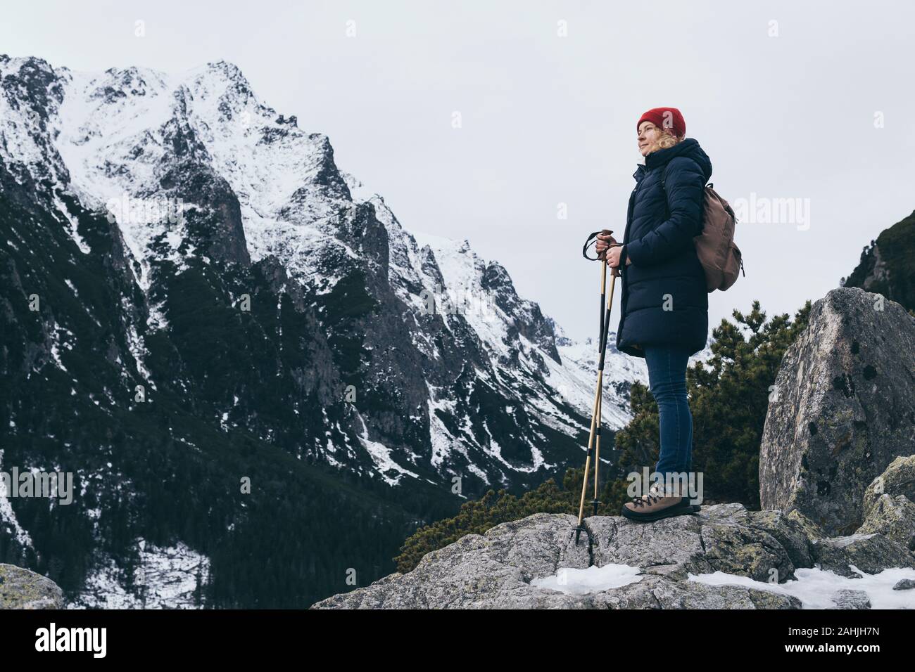 Woman trekking with walking poles in snowy High Tatra mountains in winter close to Popradske Pleso, Slovakia. Overlooking Studena dolina valley Stock Photo