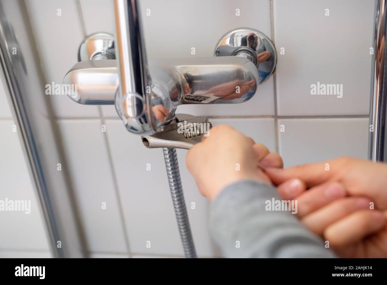 female plumber installing a chrome shower hose on a shower faucet while