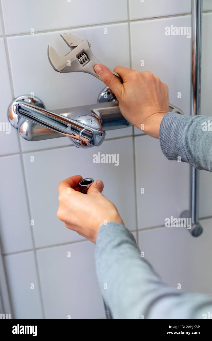female plumber installing a chrome shower hose on a shower faucet while