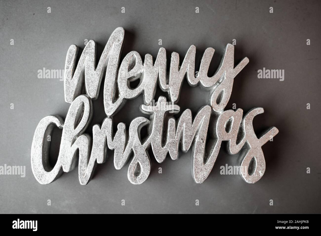 Merry Christmas Text Sign Sparkly Silver Grey in Fancy Font on Matte Textured Grey Background Stock Photo