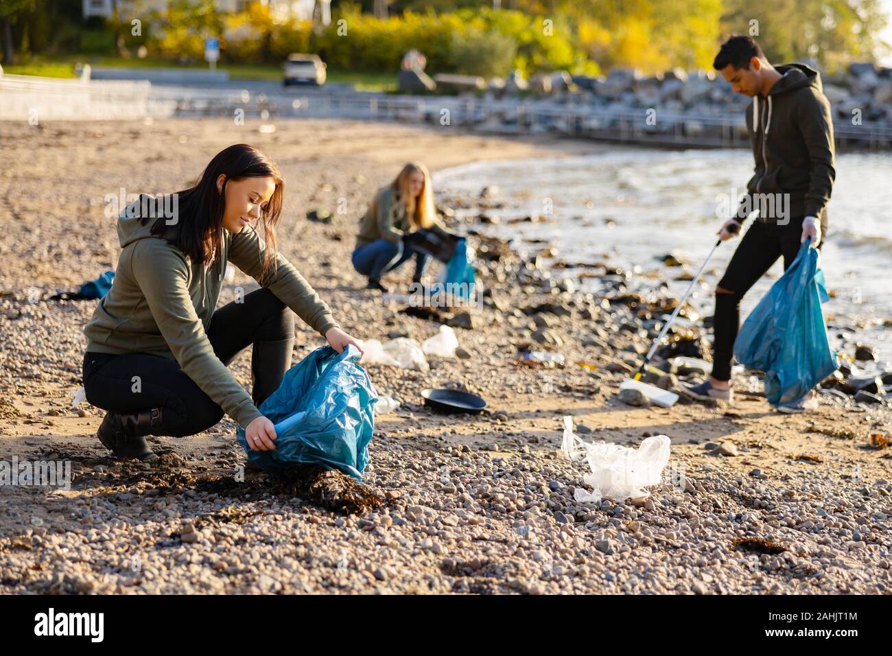 Young woman picking up garbage in bag at beach Stock Photo Alamy