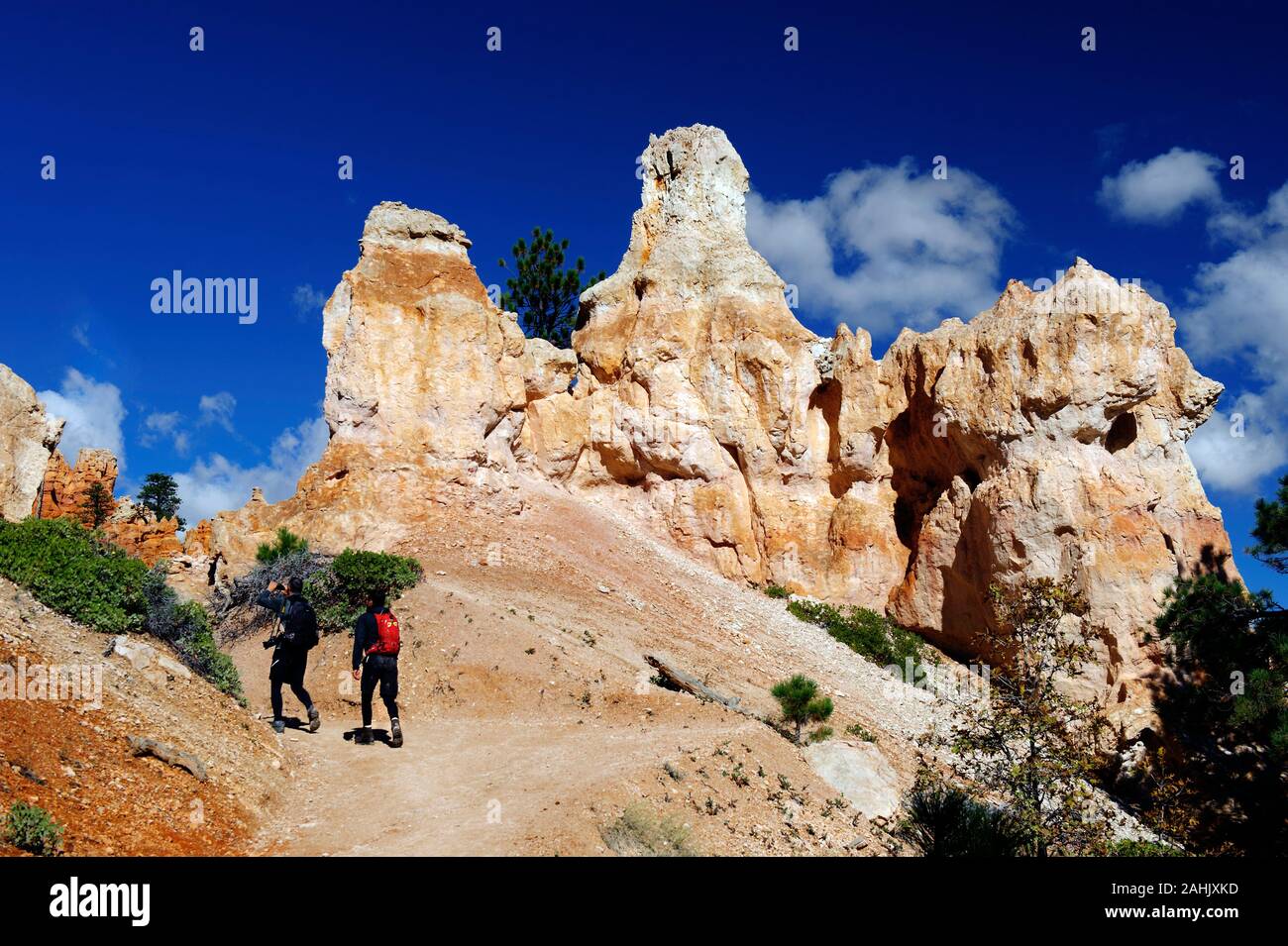 Two hikers passing by a rock formation, Bryce Canyon National Park, Utah, USA. Stock Photo