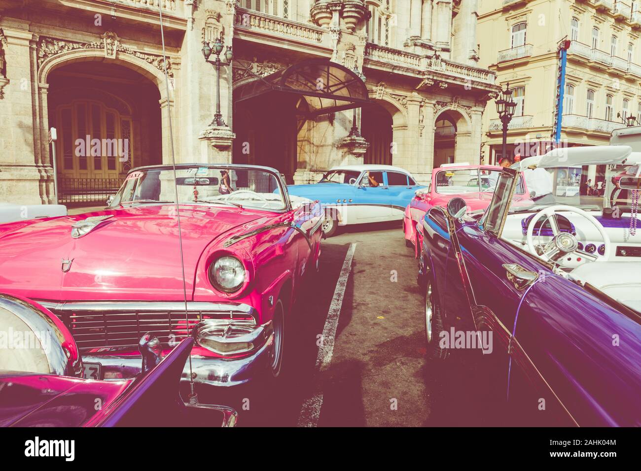 HAVANA, CUBA - DECEMBER 21, 2019: Vintage colored classic american cars front of the Galician Palace on Prado Street in Havana, Cuba. Stock Photo