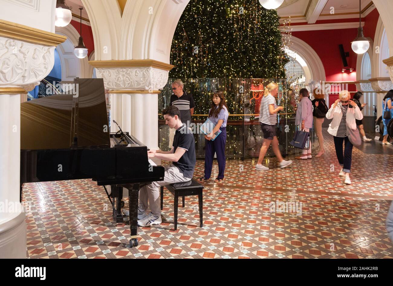 Playing a piano in public; A man playing a public piano in the Queen Victoria building mall, Sydney Australia Stock Photo