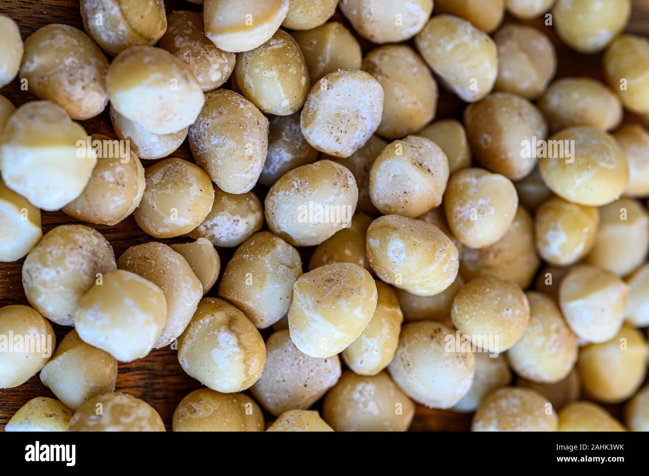 A close-up of delicious raw macadamia nuts on wooden table Stock Photo