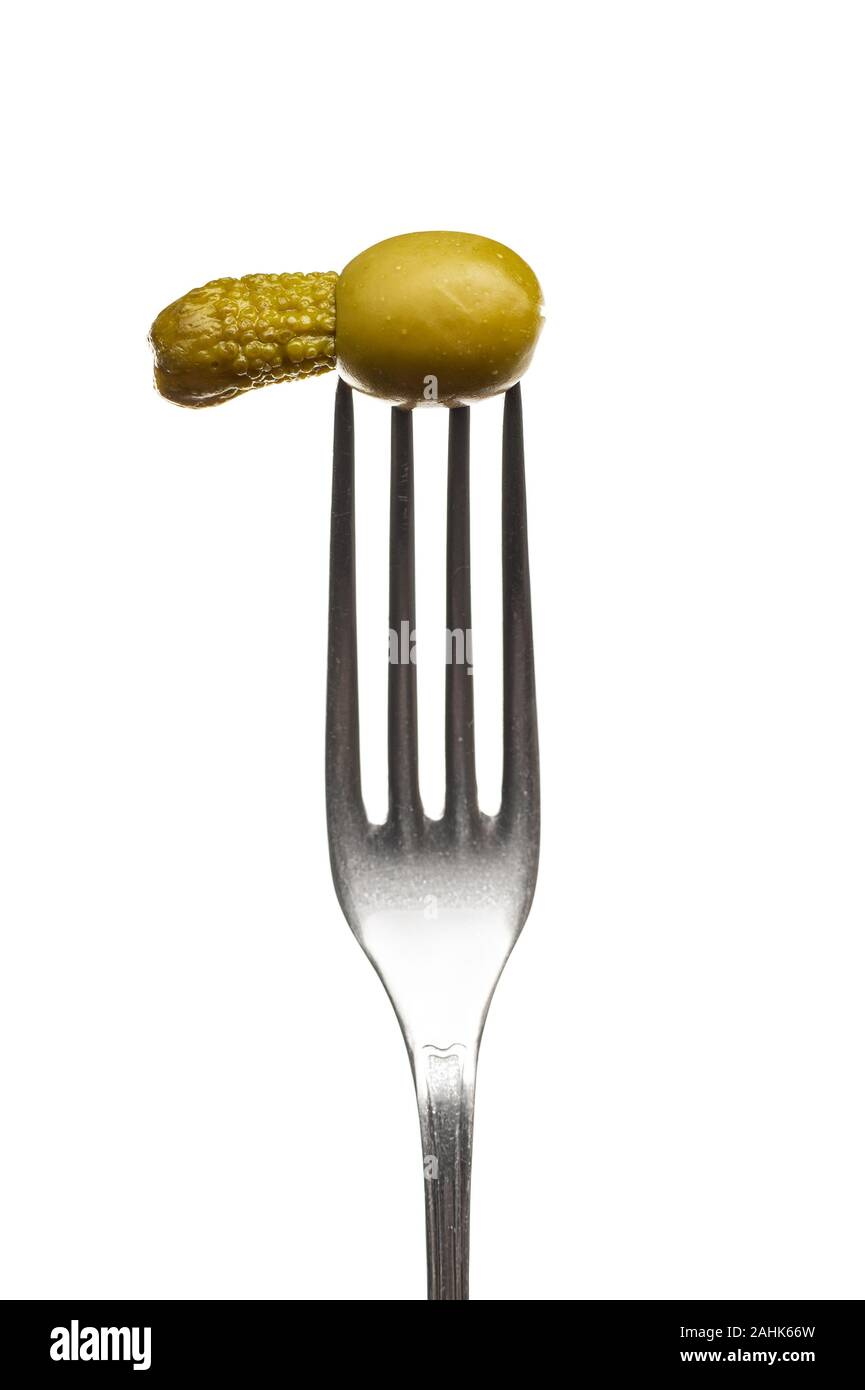 One olive a small cucumber on a fork a white background Stock Photo
